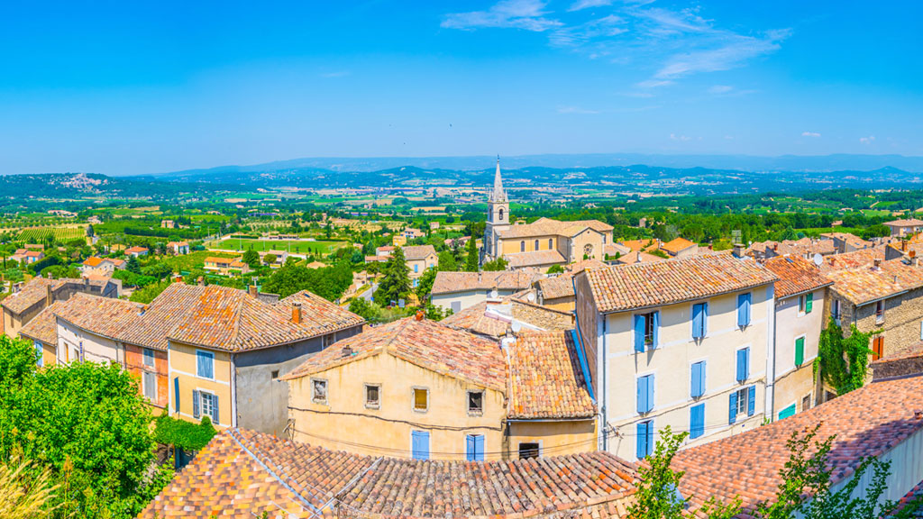 Vue sur les collines provençales depuis une fenêtre avec voilage